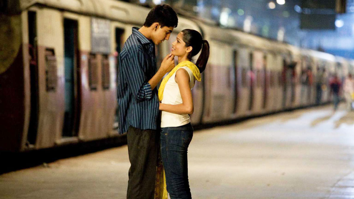 Vignette du film Slumdog Millionaire : un couple entrelacé, dans une gare de train. Le train semble arriver ou partir, et le couple s'apprête à s'embrasser.